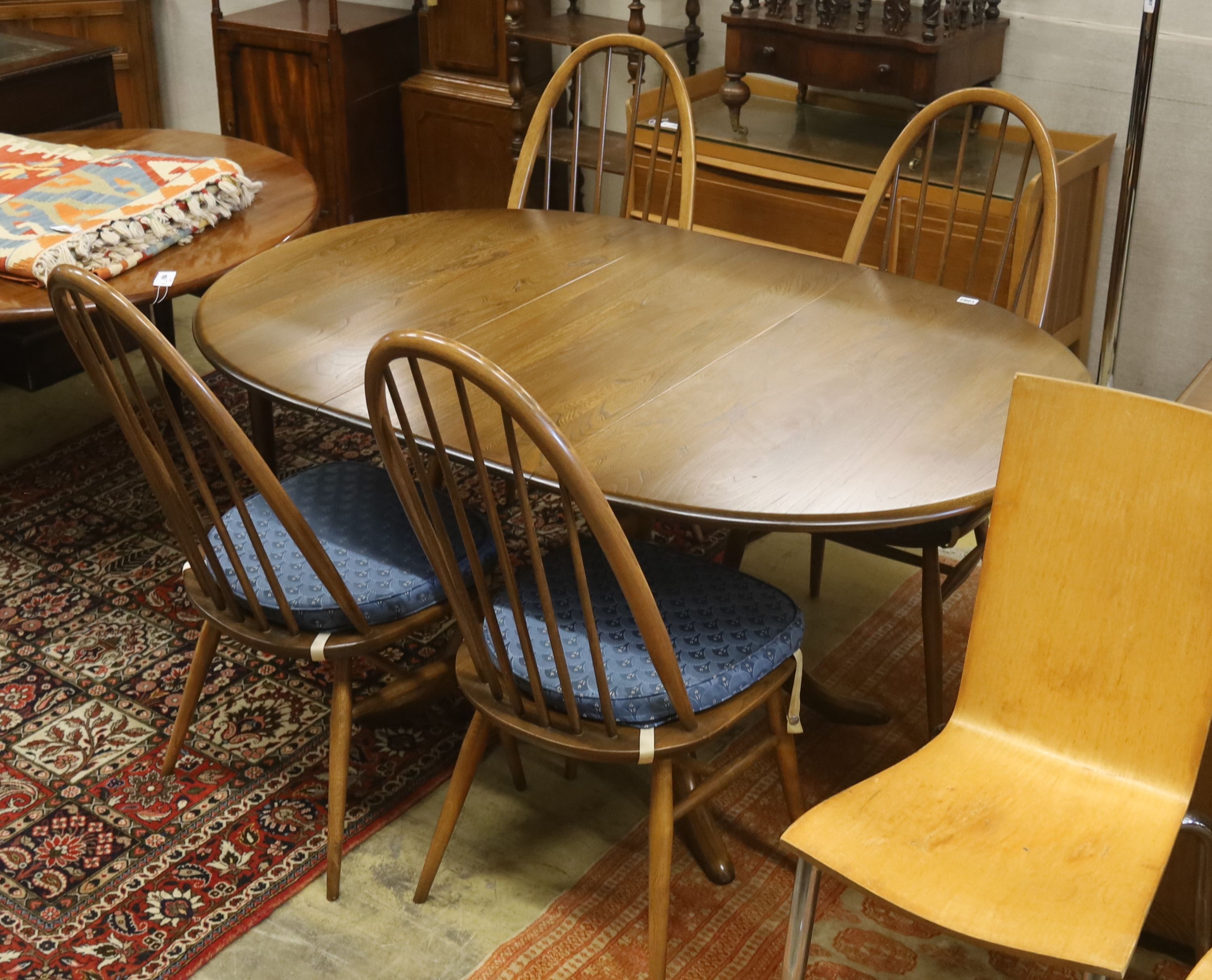 An Ercol elm oval extending dining table, 148cm extended, width 97cm, height 74cm, together with a pair of Ercol elm and beech comb back dining chairs
